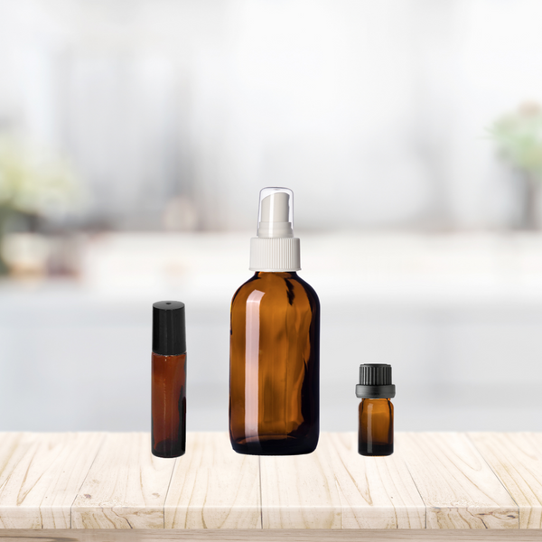 Amber Glass Bottles on Wooden Shelf to show relative bottle sizes. From Left to right: 10ml Amber Glass Roll On; 4oz Amber Glass Spray Bottle with White Spray Cap; 5ml Amber Glass Essential Oil Bottle with black Euro dropper cap.